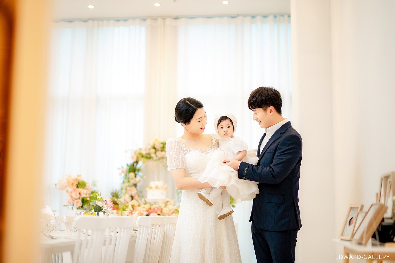 돌잔치 장소에서 아이를 가운데 안고 선 엄마와 아빠